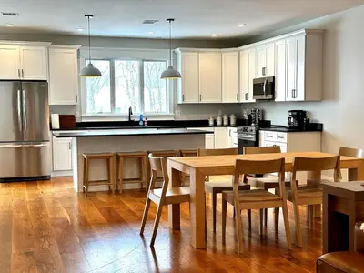 a kitchen with white cabinets and a wooden table and chairs at Luxury 3BR with King Beds in Montgomery Village in Montgomery