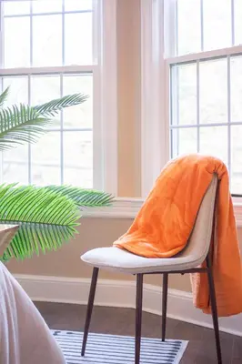 an orange blanket on a chair in a room with windows at Princeton Einstein Boutique Stay in Princeton