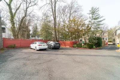 two cars parked in a parking lot next to a red fence at Princeton Einstein Boutique Stay in Princeton