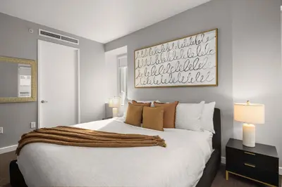a bedroom with a large white bed with a painting on the wall at Chic NYC Retreat Beside Broadway in New York