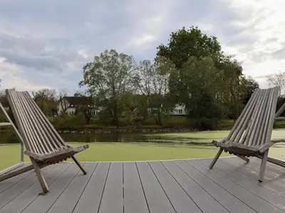 two wooden chairs sitting on a wooden deck with a pond at Bucks County Home Farm Philadelphia Dog Friendly in Warminster