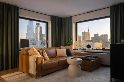 a living room with a brown couch and a large window at Stylish Midtown Escape Near Bryant Park in New York