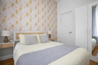 a bedroom with a white bed with a floral wallpaper at Classy 2BD Home in Manhattan in New York