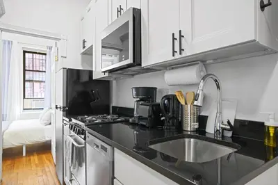 a kitchen with black counter tops and white cabinets at Classy 2BD Home in Manhattan in New York