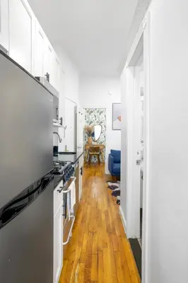 a kitchen with white cabinets and a wooden floor at Classy 2BD Home in Manhattan in New York