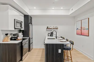 a kitchen with white walls and a counter with stools at Stylish 1BR Apartment Near Center City & University City in Philadelphia