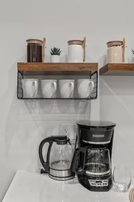 a kitchen counter with a coffee maker and cups on a shelf at Stylish 1BR Apartment Near Center City & University City in Philadelphia