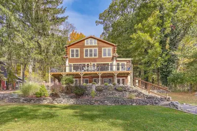 a large wooden house with a deck and a yard at Huge Waterfront Home with Dock on Lake Wallenpaupack in Hawley