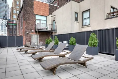 a row of chaise lounge chairs on a patio at Blueground Financial District rooftop nr Brooklyn Bridge NYC-2201 in New York