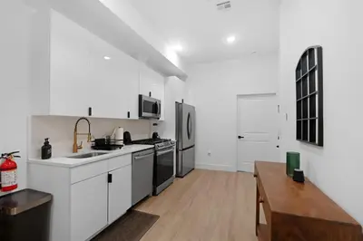 a kitchen with white appliances and a wooden table at Spacious Duplex only 15 Minutes to NYC with Firepit Perfect for Groups in Jersey City
