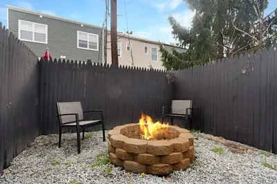 a fire pit in a backyard with two chairs and a fence at Spacious Duplex only 15 Minutes to NYC with Firepit Perfect for Groups in Jersey City
