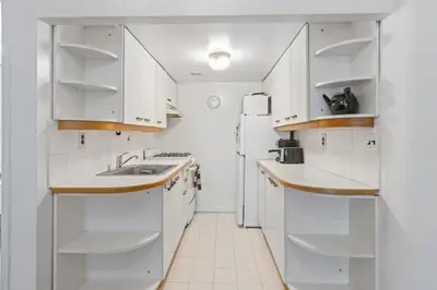 a white kitchen with a sink and a refrigerator at Stylish Studio in Central Park in Best Location Ever in New York