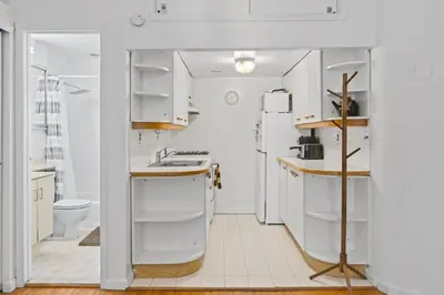 a white kitchen with a sink and a refrigerator at Stylish Studio in Central Park in Best Location Ever in New York