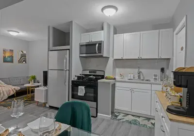 a kitchen with white cabinets and a stove top oven at Cozy Stay with Games, 15 min to NYC, Private Backyard - Sleeps 6 - NEAR METLIFE STADIUM in Jersey City