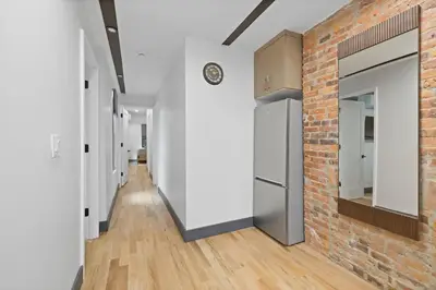 a hallway with white walls and a brick wall at Luxury and Trendy 3BR 2BA APT only 20 minutes to New York in Jersey City