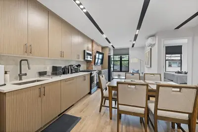 a kitchen with wooden cabinets and a table and chairs at Luxury and Trendy 3BR 2BA APT only 20 minutes to New York in Jersey City
