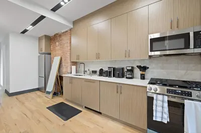 a kitchen with stainless steel appliances and wooden cabinets at New Luxury and Chic 3BR 2BA Apartment 20 Minutes to NYC in Jersey City
