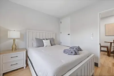a white bedroom with a large white bed and a table at New Luxury and Chic 3BR 2BA Apartment 20 Minutes to NYC in Jersey City