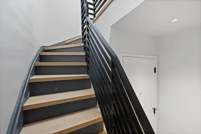 a staircase with a black rail and a white door at New Luxury and Chic 3BR 2BA Apartment 20 Minutes to NYC in Jersey City