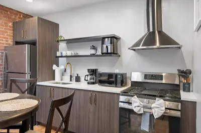 a kitchen with a stove top oven next to a table at Luxury and Modern Apt with Patio only 10 Min to Times Square in Jersey City