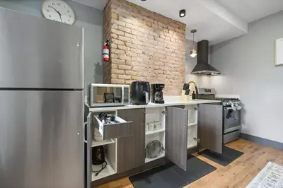 a kitchen with a refrigerator and a brick wall at Luxury and Chic 2BR 2BA Apt only 15 Mins to NYC & Hoboken in Jersey City