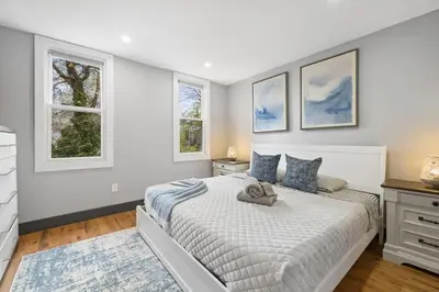 a white bedroom with a bed and two windows at Luxury and Chic 2BR 2BA Apt only 15 Mins to NYC & Hoboken in Jersey City