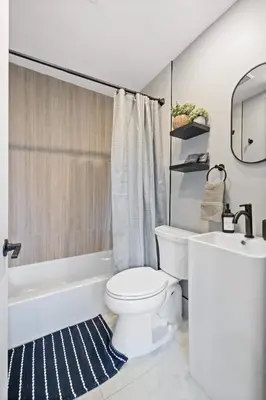 a bathroom with a white toilet and a bath tub at Luxury and Chic 2BR 2BA Apt only 15 Mins to NYC & Hoboken in Jersey City