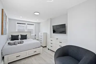 a white bedroom with a bed and a chair at New and Beautiful 2BR Apt in Prime Spot 20 Min to NYC in Jersey City