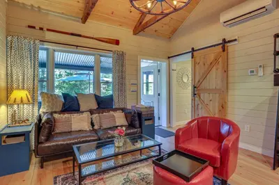 a living room with a leather couch and a red chair at Lakefront Cottage with Dock, Hot Tub and Fire Pit in Greentown