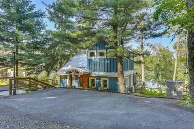 a house with a tree in front of a driveway at Lakefront Cottage with Dock, Hot Tub and Fire Pit in Greentown