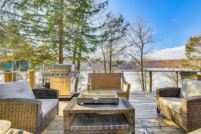 a patio with wicker furniture and a grill on a deck at Lakefront Cottage with Dock, Hot Tub and Fire Pit in Greentown