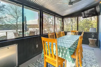 a dining room with a table and chairs and windows at Lakefront Cottage with Dock, Hot Tub and Fire Pit in Greentown