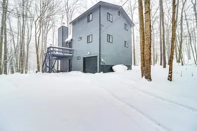 a house in the woods in the snow at Scenic Views! Clifton Twp Chalet with Fire Pit, Deck in Gouldsboro