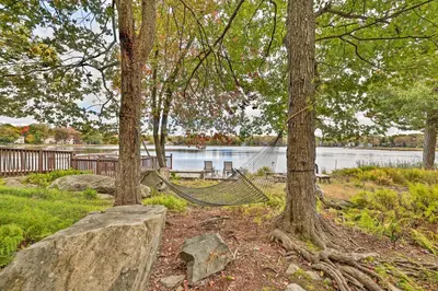 a hammock in a park with trees and a lake at Pool, Beach and Lake Access Poconos Cabin Escape! in Tobyhanna