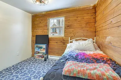 a bedroom with a bed with a wooden wall at Pool, Beach and Lake Access Poconos Cabin Escape! in Tobyhanna