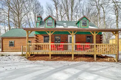 a log cabin with a large deck in the snow at Pool, Beach and Lake Access Poconos Cabin Escape! in Tobyhanna