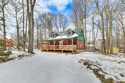 a log cabin in the woods with snow on the ground at Pool, Beach and Lake Access Poconos Cabin Escape! in Tobyhanna