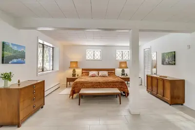a bedroom with a bed and a dresser and a table at Vibrant Hideaway on Shores of West Emerald Lake! in Long Pond