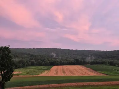 a dirt field with a hill in the background at Just Like Home, Overlooks Maple Grove Raceway in Mohnton
