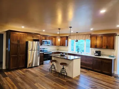 a kitchen with wooden cabinets and a stainless steel refrigerator at Just Like Home, Overlooks Maple Grove Raceway in Mohnton