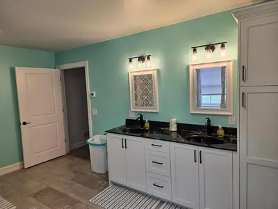 a bathroom with two sinks and a window and green walls at Just Like Home, Overlooks Maple Grove Raceway in Mohnton