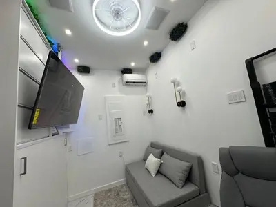 a living room with a couch and a flat screen tv at Modern Tiny Home Fast NYC Access Private in Jersey City