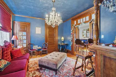 a living room with a purple couch and a chandelier at The Manheim Manor in Manheim