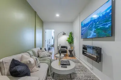 a living room with a couch and a flat screen tv at New Calm Cocoon by Train We Pay Half Parking, Sleeps 6 in Hoboken