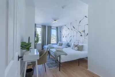 a white bedroom with a bed and a desk and a table at New Calm Cocoon by Train We Pay Half Parking, Sleeps 6 in Hoboken