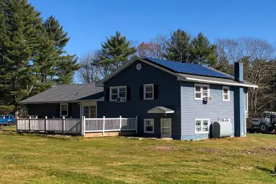 a blue house with a solar roof on a yard at Family River Valley Retreat with Fireplace in Sparrow Bush
