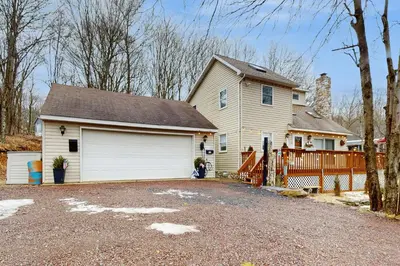 a white house with a garage and a driveway at Lakeside Escape in Blakeslee
