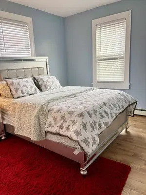 a bedroom with a bed with a red rug and two windows at Heavenly Retreat Luxury 3 Bedrooms 1 Bathroom in East Orange