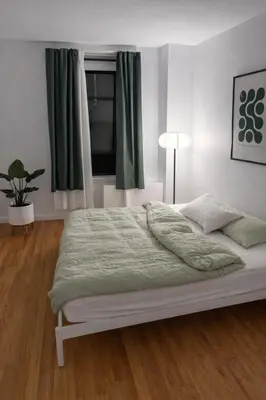 a bedroom with a bed with green sheets and a window at Elegant NYC Apartment with Designer Touches in New York
