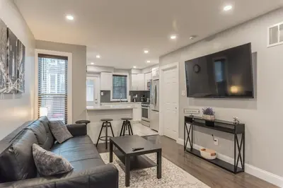 a living room with a couch and a kitchen at University City Executive Modern 3BR 2BA Within 5 min to Drexel, University of Pennsylvania, & Children's Hospital of Pennsylvania in Philadelphia